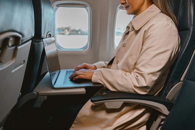 Close up van vrouwelijke passagier zittend in het vliegtuig en werkende laptop tijdens de vlucht