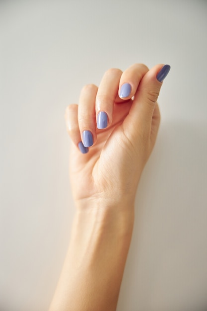 Close up van vrouwelijke pols en vingers met gelakte nagels in blauw geïsoleerd op een witte achtergrond