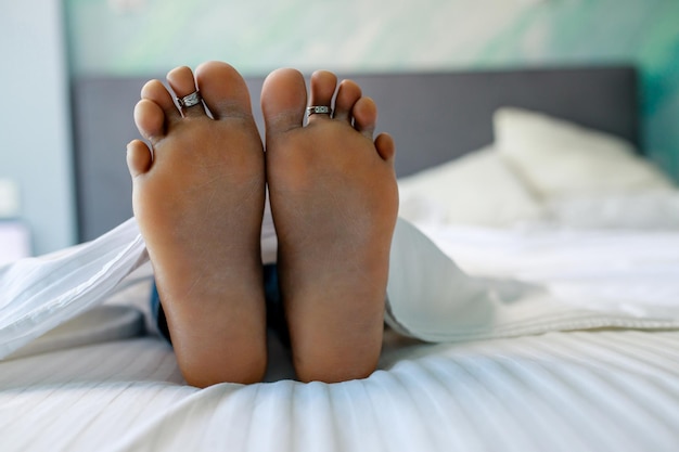 Close up van vrouwelijke voeten in bed in de slaapkamer onder deken