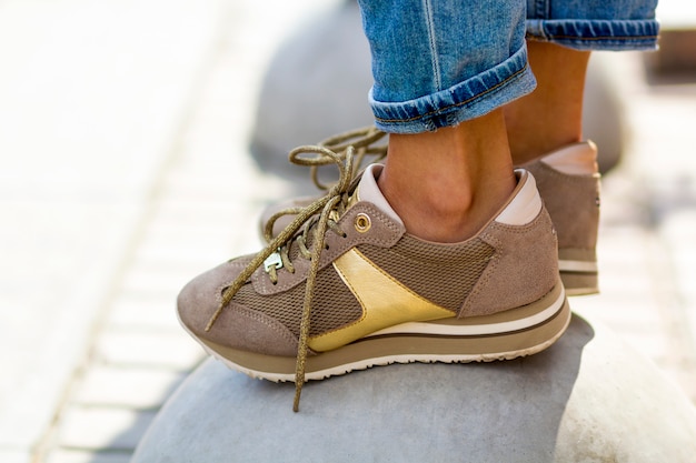 Close-up van vrouwelijke voeten in beige sneakers. Vrouw in modieuze schoenen buitenshuis