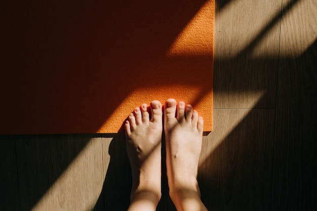 Foto close-up van vrouwelijke voeten op yogamat in zonlicht