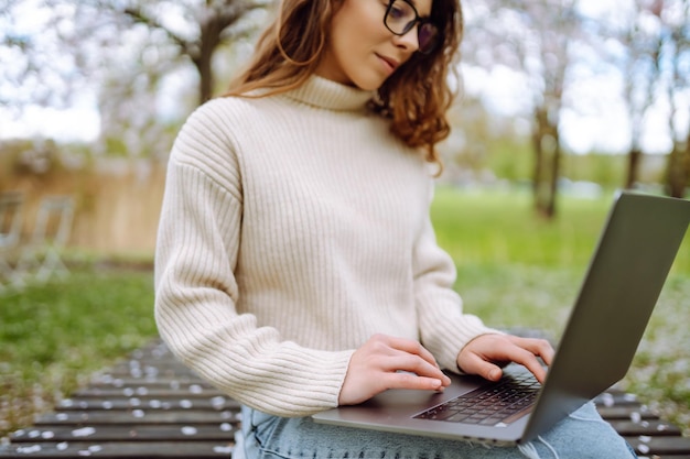 Close-up van vrouwen die met de hand op een laptop typen met een notepad aan een tafel in het park Concept van afstandswerk