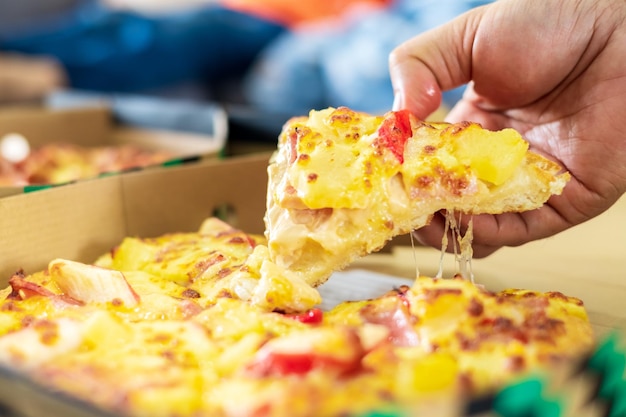 Close-up van vrouwen handen nemen een stukje cheesy smakelijke verse pizza Food delivery home concept