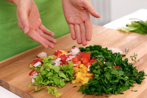 Close-up van vrouwenhanden die in de keuken koken Huisvrouw die verse salade aanbiedt Vegetarisch en gezond kookconcept