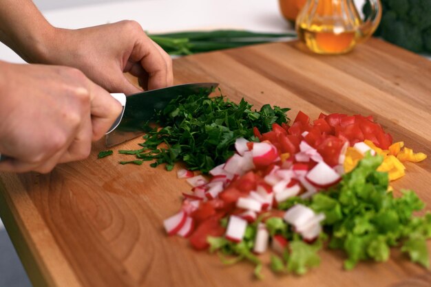 Close-up van vrouwenhanden die in de keuken koken Huisvrouw die verse salade snijdt Vegetarisch en gezond kookconcept