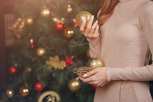 Close-up van vrouwenhanden met ballonnen op de achtergrond van een kerstboom