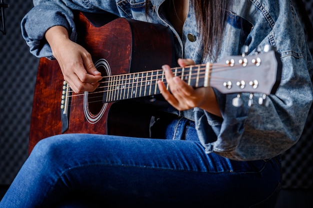 Close-up van vrouwenvingers die bemiddelaar vasthouden met een gitaar die een lied opneemt in de opnamestudio