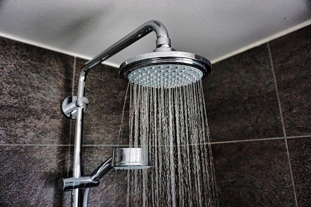Close-up van water dat uit de douche valt in de badkamer thuis