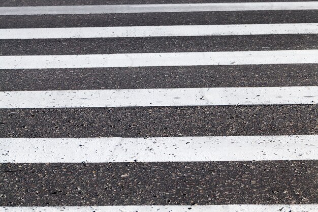 close-up van wegmarkering bevindt zich op de rijbaan, witte lijnen van een voetgangersoversteekplaats