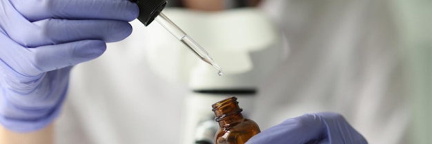Close-up van wetenschapper die monster van vloeistof uit fles neemt met pipet vrouwelijke chemicus aan het werk