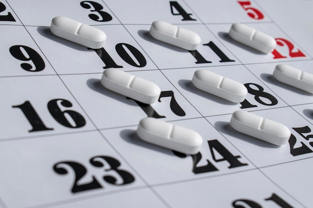Close up van witte pillen op een kalender. Medicatieplan, schema, lijst of kalenderconcept.