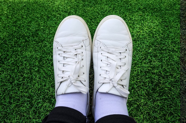 Close-up van witte sneakers op grasoppervlak