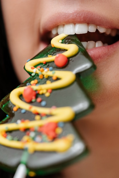 Close-up van witte tanden die een zoet de glimlachconcept van de kerstboomlolly proberen te bijten