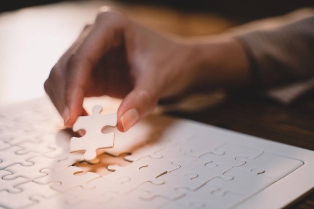 Close-up van zakelijke handen die puzzelsucces en doelrealisatie verbinden de laatste puzzel is de link van alle stukken strategische planning of een oplossing voor het management