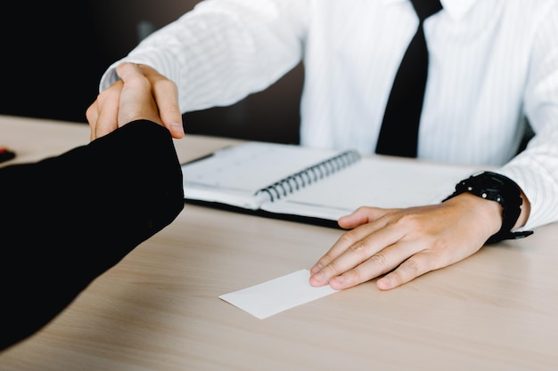 Close-up van zakenlieden die elkaar de hand schudden aan het bureau in het kantoor