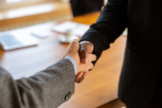 Close-up van zakenlieden die handen schudden in de vergaderruimte, een deal sluiten, een succesvolle overeenkomst of samenwerking sluiten. Concept van financiën en zaken, contracten, partnerschap, gemeenschap en teamwork.