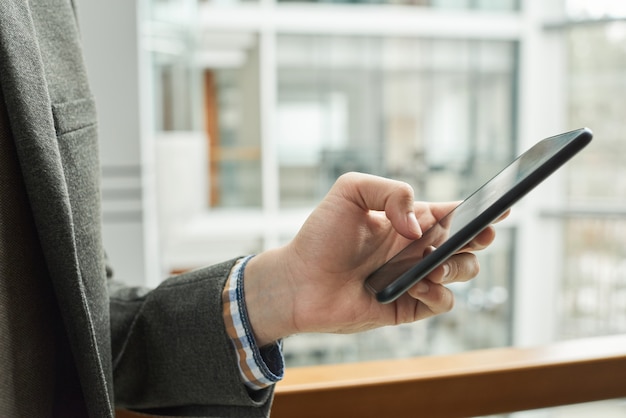 Close-up van zakenman die een bericht typt op mobiele telefoon die buiten staat