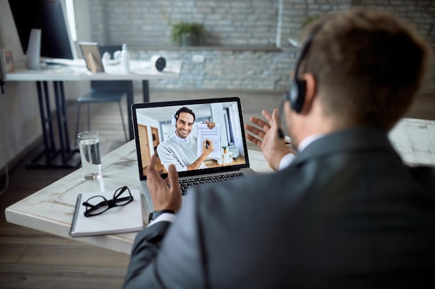 Close-up van zakenman die een videoconferentie heeft met zijn collega via laptop op kantoor