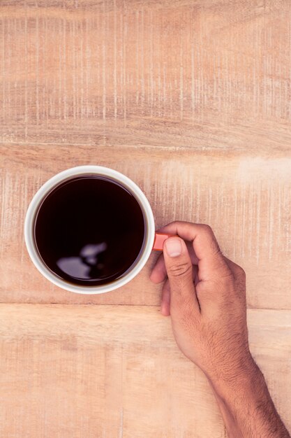 Close-up van zakenman die zwarte koffie op bureau houdt