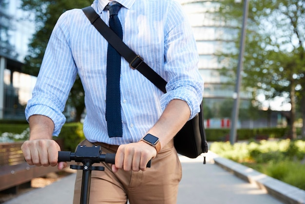 Close-up van zakenman woon-werkverkeer om te werken op scooter