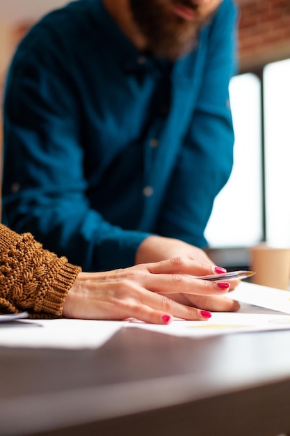 Close-up van zakenmensenhanden die marketingpapierwerken analyseren die bij bedrijfspresentatie in startbureau werken. Collega's die bij marketingproject werken die bedrijfsstrategie bespreken