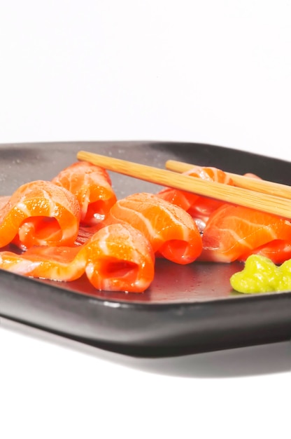 Close-up van zalm met eetstokjes in een bord op witte achtergrond