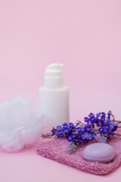 Close-up van zeep; handdoek; lavendel bloem; luffa en cosmetische fles op roze oppervlak