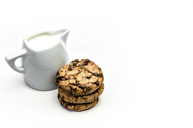 Close-up van zelfgemaakte chocoladeschilferkoekjes met een kruik melk op een witte achtergrond..