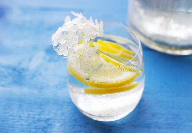 Close-up van zelfgemaakte limonade in een glas op de blauwe houten tafel met witte bloemen