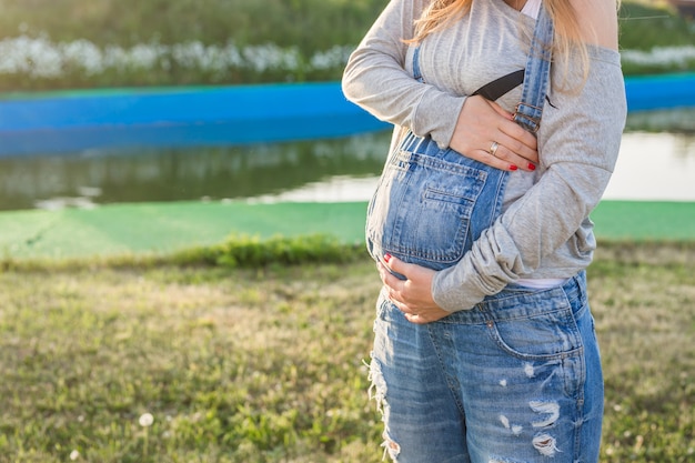 Close-up van zwangere vrouw die haar buik buitenshuis knuffelt