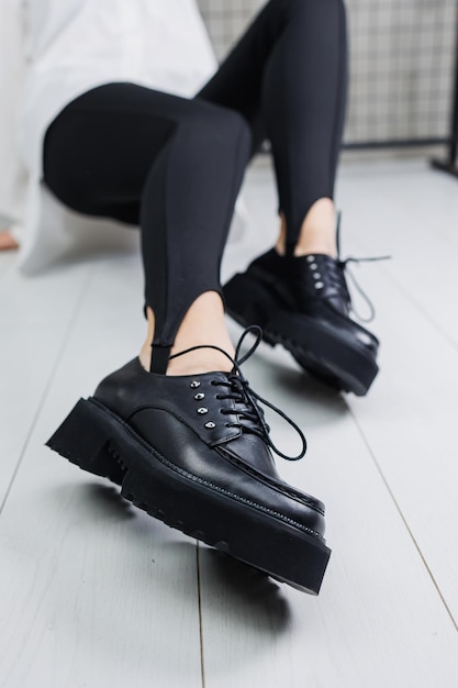 Close-up van zwarte leren veterschoenen op vrouwelijke benen in zwarte leggings Stijlvolle herfstschoenen voor dames