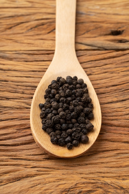 Close-up van zwarte peperkorrels op een houten lepel. Voedsel achtergrond.