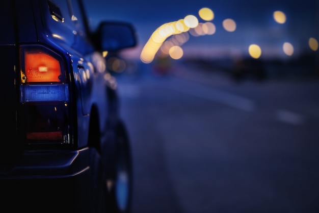 Close up van zwarte SUV auto achterlicht op de weg tijdens schemering, selectieve focus met zeer ondiepe scherptediepte.