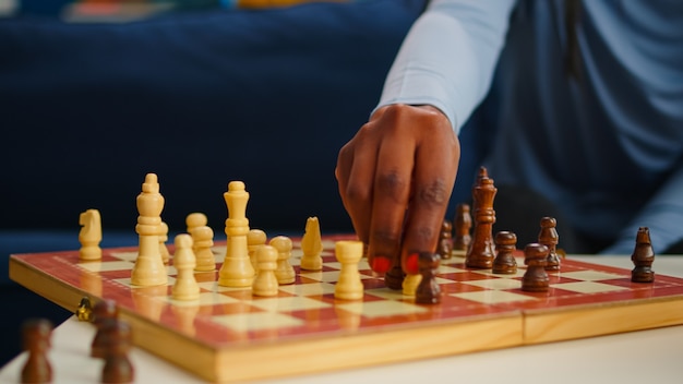 Close up van zwarte vrouw bewegende schaakstukken aan boord vrije tijd doorbrengen met vrienden. Groep mensen die plezier hebben in de huiskamer en ontspannen bordspellen spelen, diverse vrouwen die van competitie genieten