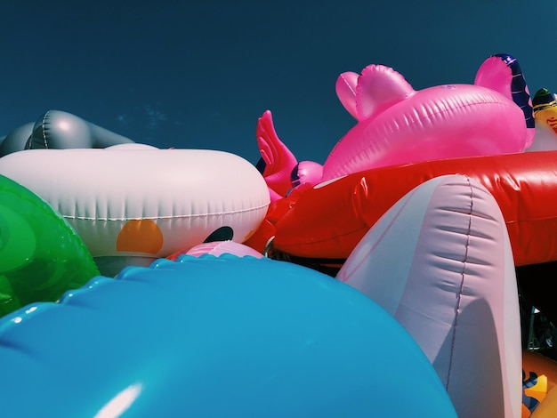 Photo close-up of various inflatables beach toys on beach against clear summer sky