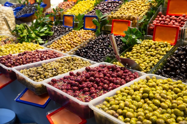 Close up of various olives standing in plastic container on\
deli counter in market place