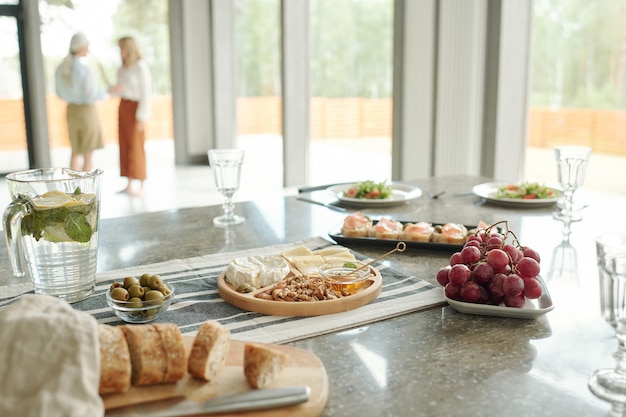 Close-up of various snacks such as appetizers, cheeses and grapes on dining table