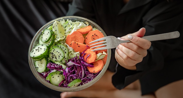 Закройте вегетарианский салат из свежих овощей в женских руках.
