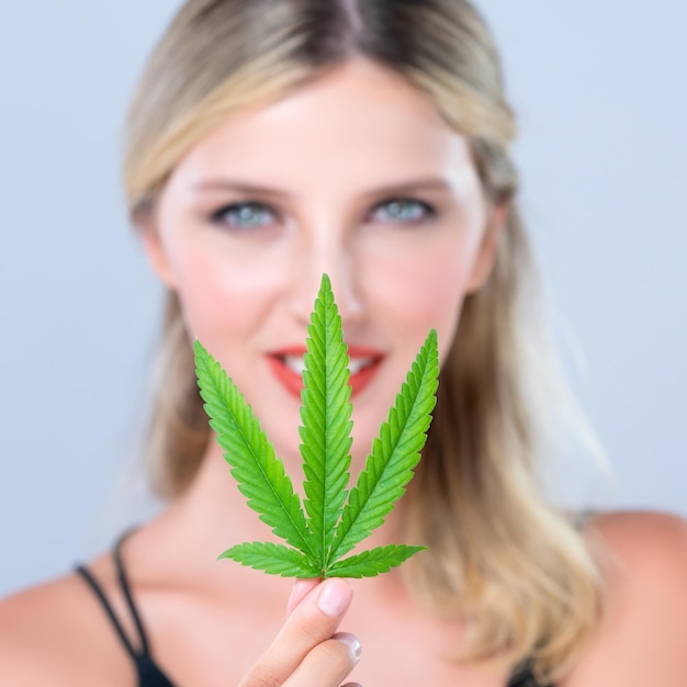 Close-up verleidelijke vrouw portret houdt groen blad als concept van cannabis schoonheid