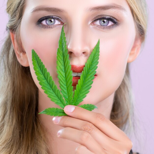 Close-up verleidelijke vrouw portret houdt groen blad als concept van cannabis schoonheid