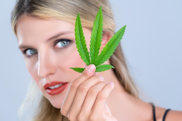Close-up verleidelijke vrouw portret houdt groen blad als concept van cannabis schoonheid