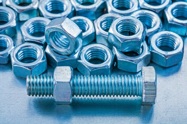 メタリックな背景の建設コンセプトにステンレスねじナットとボルトのバージョンをクローズアップ