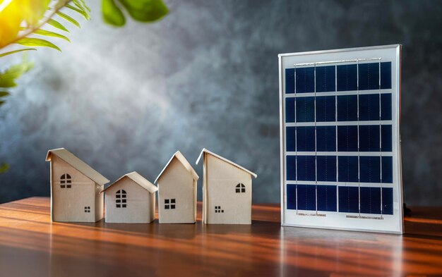 Close up view of alternative energy engineer pointing at solar panels for future energy in studio A small cardboard house and a solar panel close up