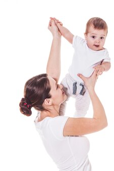 Vista ravvicinata di una giovane madre attraente con il suo bambino vestito di bianco su sfondo bianco
