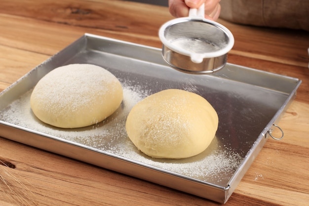 Vista ravvicinata del panettiere che impasta la pasta. pane fatto in casa. mani che preparano la pasta di pane sulla tavola di legno. preparazione del pane tradizionale fatto in casa. mani di donna che impastano pasta fresca per fare il pane