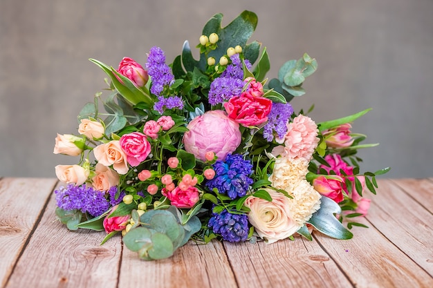 Close up view of a beautiful bouquet of mixed coloful flowers on wooden table.