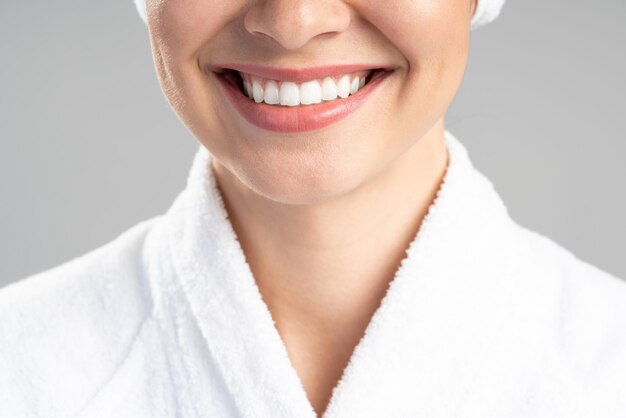 Close up view of the beautiful young woman in a white bath robe isolated on grey background with copy space. Happy woman enjoying after body treatment