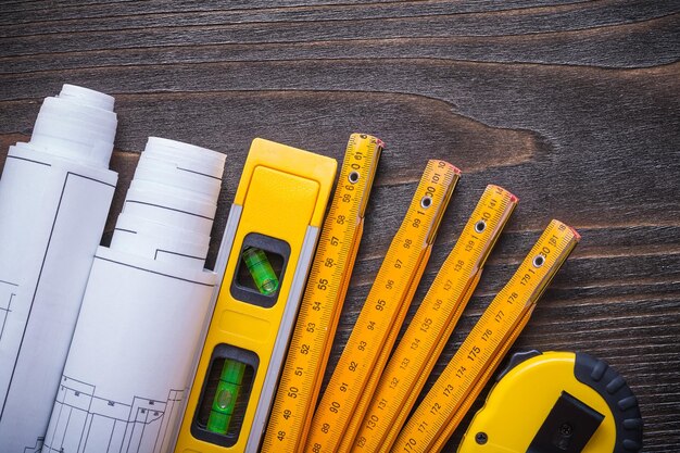 Close up view of blueprint rolls construction level tapeline
and wooden meter on vintage wood board maintenance concept