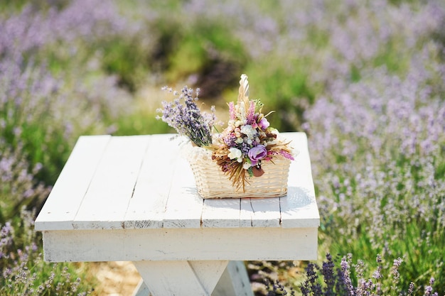 Close up view of bouquet of lavender flowers in basket that lying on the white table in field