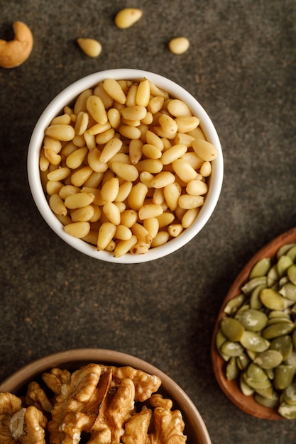 Close-up view of bowl with pine nuts nuts over dark table